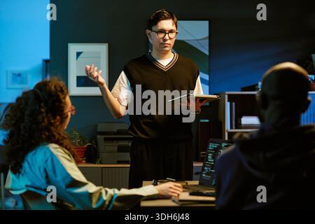Young Adult Caucasian Man Explaining Project Details to Diverse Coworkers Stock Photo
