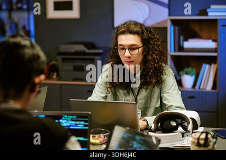 Young Adult Caucasian Man Developing Software on Laptop in Contemporary Office Stock Photo
