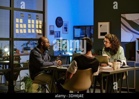 Multiethnic Young Adults Collaborating during Evening Office Meeting Stock Photo