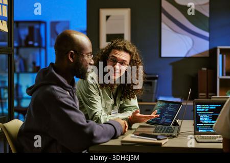 Young Caucasian Man Explaining Programming Code to Black Man in Office Stock Photo