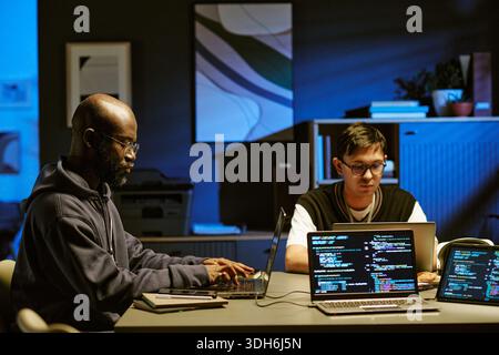 Young Adult Black Man and Asian Man Collaborating on Software Development Stock Photo