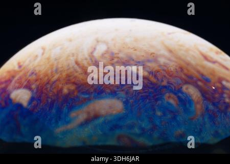 Vivid, swirling patterns in blue, orange, and white resembling a planet’s surface against a dark background, evoking cosmic and abstract themes. Stock Photo