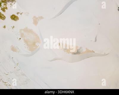 Aerial view of vast sandy dunes sculpted by wind and time create a serene landscape, the pale sand contrasting with patches of green vegetation, Betty Stock Photo