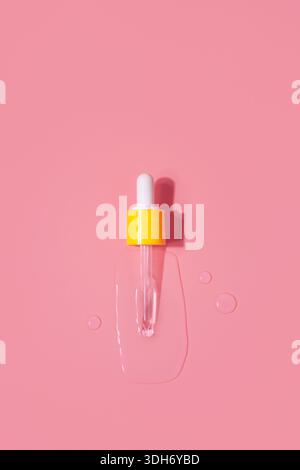 Yellow pipette drops of serum moisturized bottle on pink background. Essence transparent hyaluronic acid Stock Photo