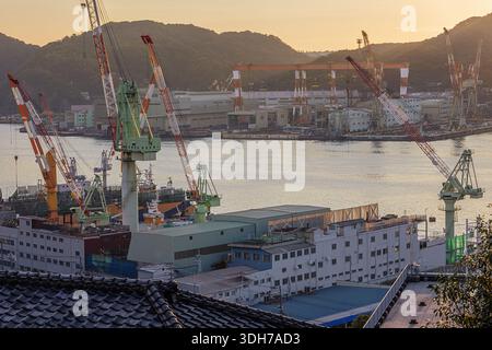 Shipyards along the Uragami River lit by the setting sun, seen from the slopes of the Glover Garden Stock Photo