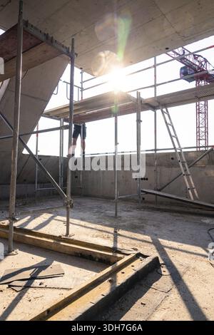 Construction site scene with scaffolding and sunlight, construction worker working on construction, carpentry, new building, Stuttgart, Germany Stock Photo