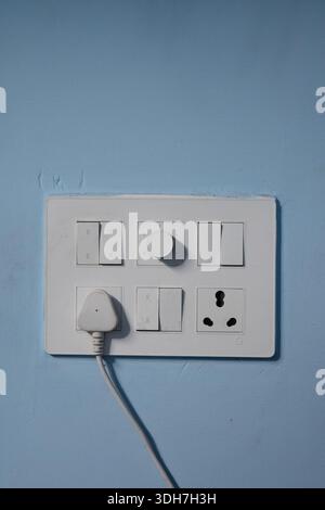 White Electrical Switchboard with Plug on Blue wall Stock Photo