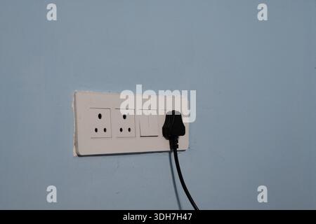 White Electrical Switchboard with Plug on Blue wall Stock Photo
