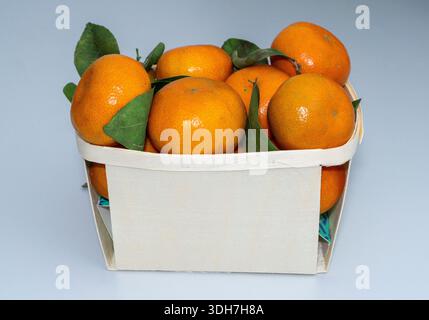Fresh Organic Clementines with Leaves in Eco-Friendly Wooden Basket Stock Photo