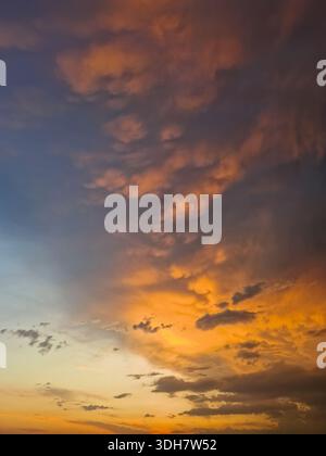 Expansive view of a dramatic sunset sky filled with textured mammatus and altocumulus clouds. Breathtaking natural scene with the horizon glowing in f Stock Photo