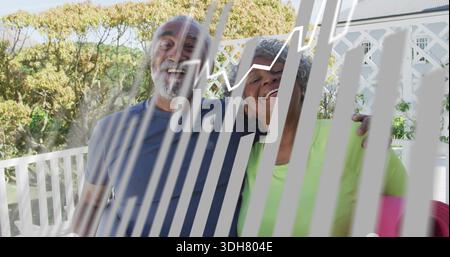Smiling seniors on porch, wearing blue-tee lime-top, with pink-cushion, white-rail, white-stripes Stock Photo