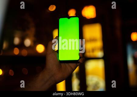 hand holding cell phone with screen on camera in the city at night with car lights in background Stock Photo