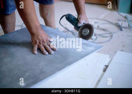 hands of latin worker cutting a tile with the electric grinder Stock Photo