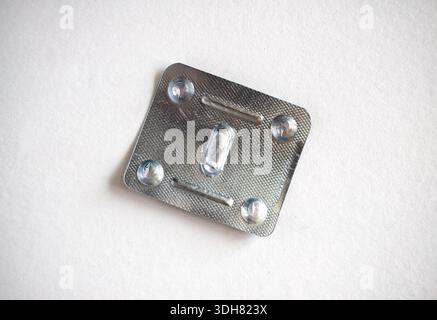 Empty metal blister pack with one pill isolated on white background. Metal blister for capsules. Healthcare and medicine concept, top view Stock Photo