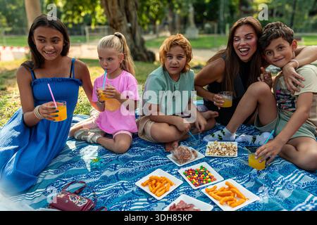 Happy family enjoying picnic with snacks and drinks in park Stock Photo