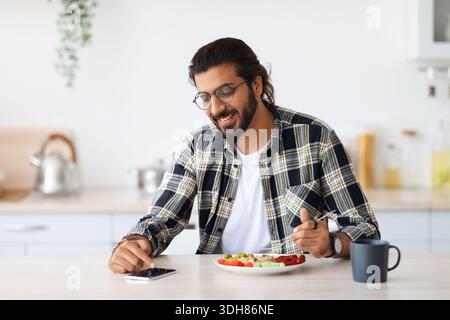 Handsome indian man using cellphone while having breakfast Stock Photo