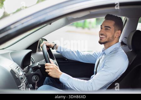 Excited arab guy going to office, driving his car Stock Photo