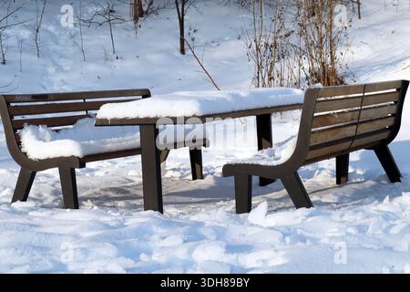 Snow-covered table and benches in a winter park Stock Photo