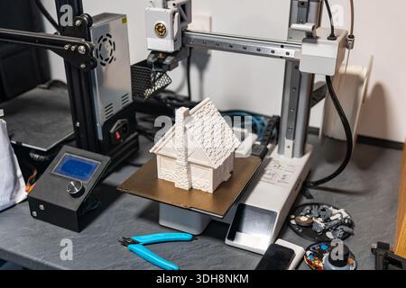 Plastic 3d printer working on printing a small house to scale for board games. Stock Photo
