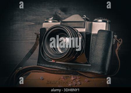 Old aged film camera in black leather cases photography close-up. Vintage camera on black wooden background Stock Photo