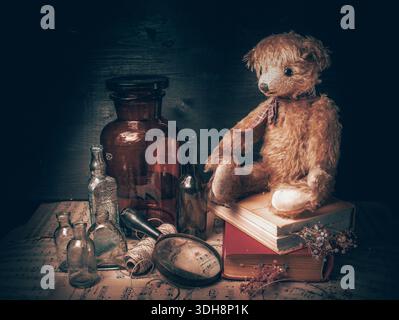 Vintage teddy bear sitting near old books with dried flowers inside yellow pages. Retro style still life Stock Photo
