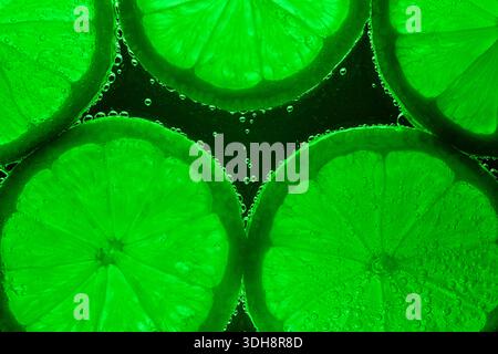 A close up of green citrus fruit with bubbles in the background. The bubbles are floating around the fruit, giving it a playful and whimsical appearan Stock Photo