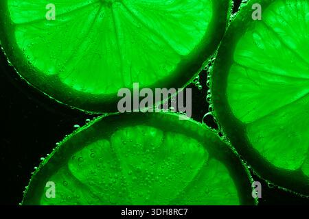 A close up of four green citrus fruits, specifically lime slices. The lime slices are arranged in a way that highlights their vibrant green color and Stock Photo