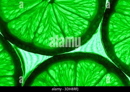 A close up of green citrus fruit, specifically lime slices. The slices are arranged in a way that highlights their vibrant green color and the intrica Stock Photo