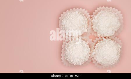 Four white coconut balls in a row. The background is pink Stock Photo