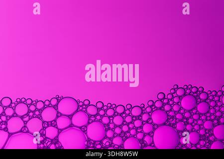 A pink background with a purple line of bubbles. The bubbles are all different sizes and are scattered throughout the image Stock Photo