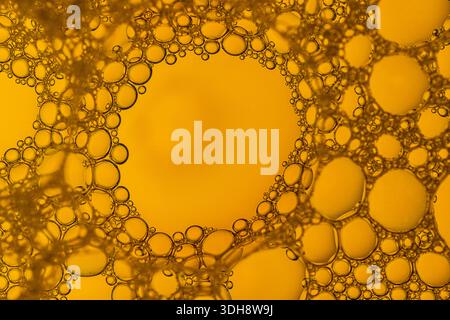 The image is of a yellow liquid with many bubbles in it. The bubbles are scattered throughout the liquid, creating a sense of movement and energy. Sce Stock Photo