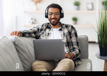 Relaxed middle-eastern guy watching movie online, using laptop Stock Photo