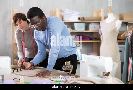 Two sewing workshop workers draw patterns on paper Stock Photo