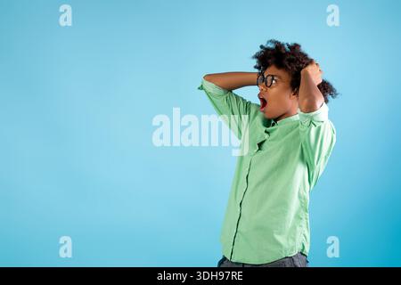 Surprised black guy looking at free space, touching head and shouting WOW over blue studio background Stock Photo