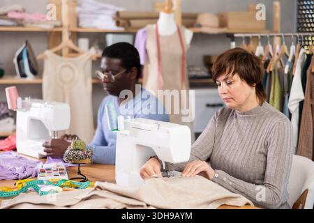 Two tailors working at sewing machines in tailoring studio Stock Photo
