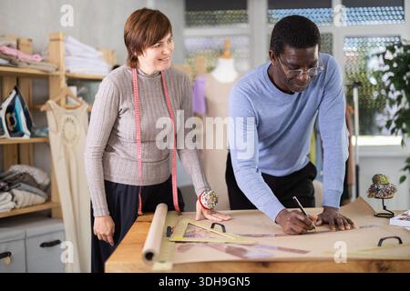 Two sewing workshop workers draw patterns on paper Stock Photo