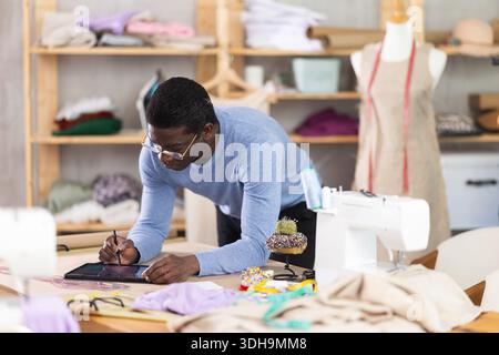 African American man tailor creates sketch of dress on tablet Stock ...
