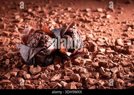 Dark chocolate muffins on chopped dark chocolate and cocoa. Muffins on chocolate and cocoa background. Stock Photo