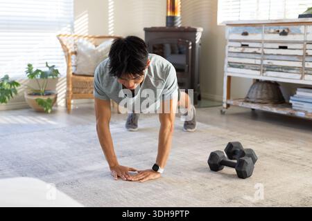 Black hex dumbbells are resting on light-gray rug while sunlight is streaming through blinds Stock Photo