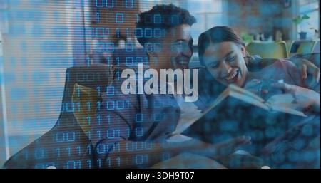Reading couple sitting on sofa at home sharing open book, with yellow cushion and binary overlay Stock Photo