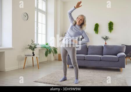 Happy senior woman doing physical exercise, side bends and stretching workout Stock Photo