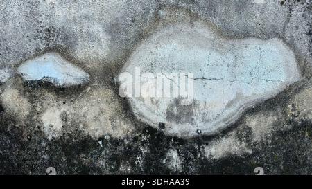 High-detail close-up of a weathered concrete wall featuring grunge textures, black mold patches, and layers of peeling light blue and white paint. Stock Photo