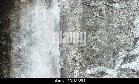 Close-up view of a rough, weathered concrete wall featuring irregular patches of faded light blue paint and dark organic staining, creating an abstrac Stock Photo