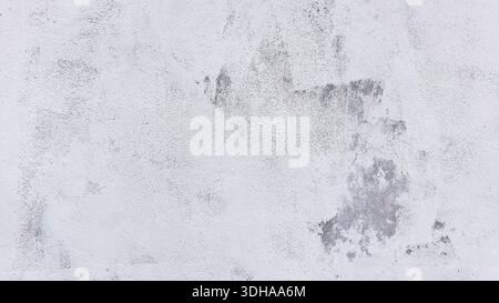 A high-resolution, close-up shot of a weathered, light-colored wall with visible gray patches, cracks, and peeling paint, creating a gritty, industria Stock Photo