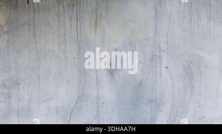 A high-resolution background of a weathered, mix grey painted concrete wall with water stains, fine cracks, and a rough, aged texture. Stock Photo