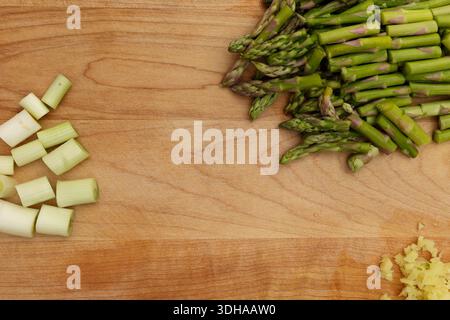 Top-Down Shot of Chopped Asparagus, Green Onion, and Ginger on Wooden Cutting Board Stock Photo