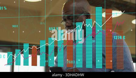 Reviewing senior African American man in glasses studying phone in office with glass data display Stock Photo