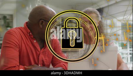 Leaning red-shirted man and patterned-blouse woman using laptop at home, with gold padlock overlay Stock Photo