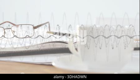 Featuring notebook with rectangular glasses and pen lying on pages on wooden desk, waveform overlay Stock Photo