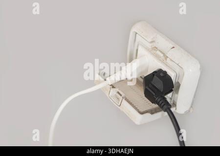 Power cord plugged into outdoor electrical wall socket. Dual covered electricity power outlets on cement wall. Copy space. Stock Photo